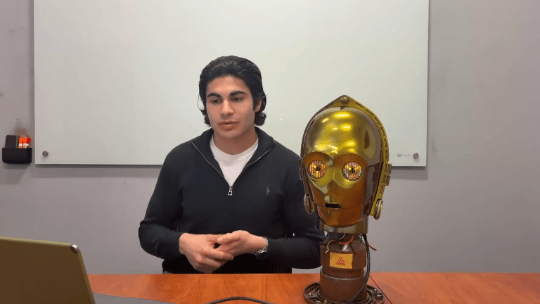 Man sitting next to C-3PO replica head