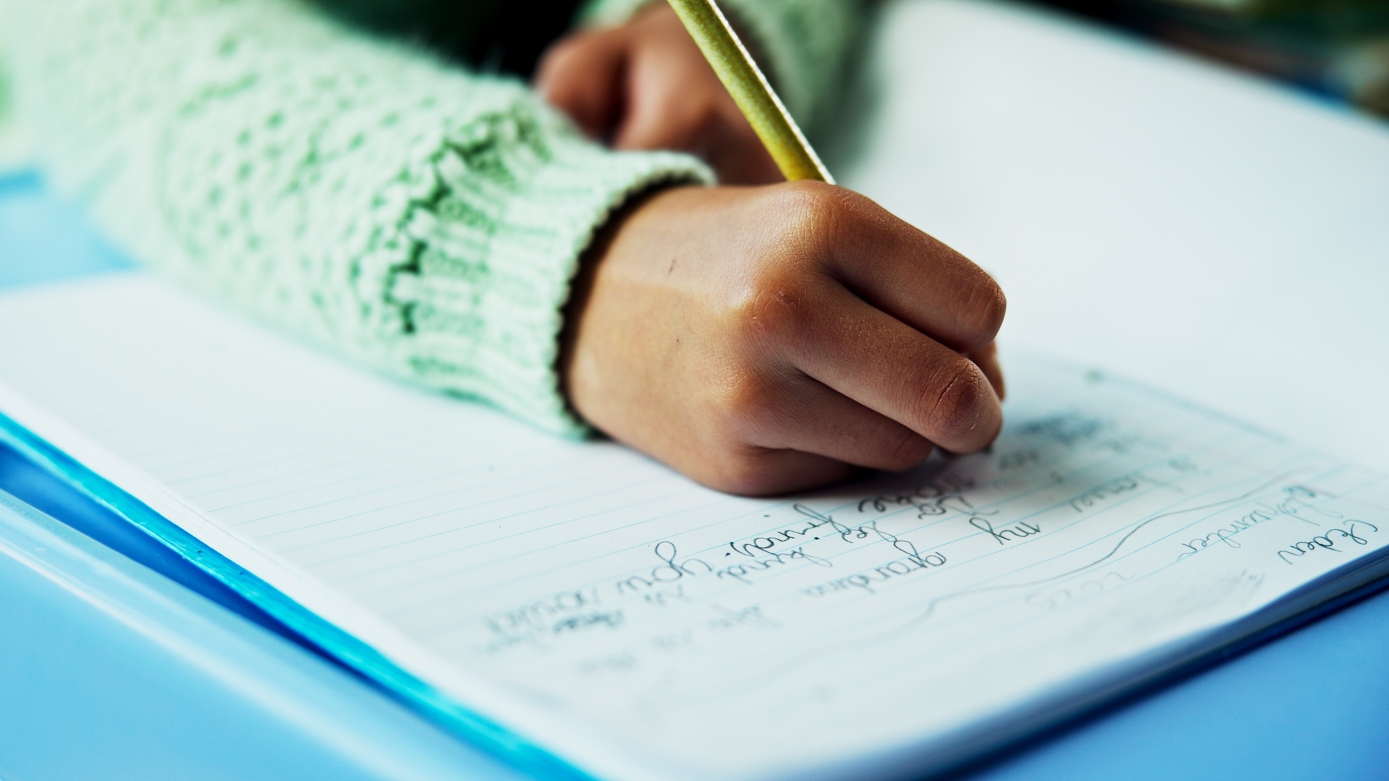 Close up of child hand writing in notebook