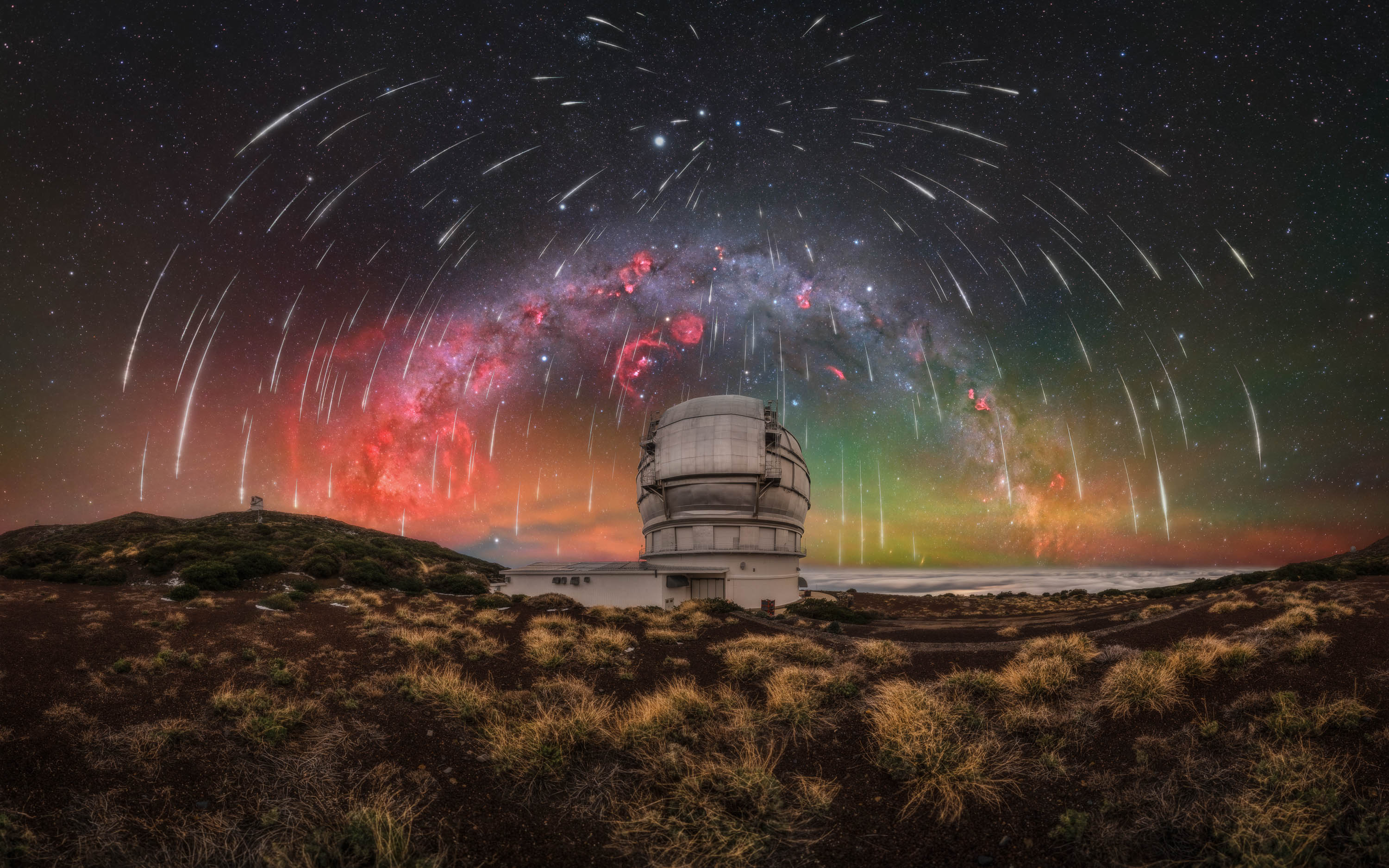 This winter Milky Way panorama captures a sky filled with Geminid meteors above the Gran Telescopio Canarias, the largest optical telescope in the world. My first trip to La Palma was an intense and unpredictable experience, from storms and summit snowfall to strong winds, rain, and brief windows of clear skies. For the first three nights, we were confined to the southern part of the island, as the road to the Roque de los Muchachos Observatory remained closed, forcing us to search for clear conditions elsewhere. Reaching the summit seemed increasingly unlikely, until the fourth day, when the road finally reopened. We immediately made our way up, filled with anticipation. After scouting compositions and preparing for the night, clouds once again moved in, putting everything at risk. Rather than giving up, we waited, constantly checking the sky for any sign of improvement. Around midnight, the first stars began to appear, and we quickly headed to the Gran Telescopio Canarias. Above us, the sky opened into a field of stars, while a layer of clouds remained below, creating a striking contrast with the illuminated structure of the telescope. Although the dome could not be opened due to humidity, the experience of witnessing such dark skies for the first time was remarkable, with the Milky Way appearing almost three-dimensional. This was also my first successful capture of the Gum Nebula, adding a unique element to the composition. The final image is the result of an extensive post-processing workflow, combining meteor data registered using Auriga RegiStar from six cameras over five nights on La Palma. All RGB frames were captured using the Capture the Night Astro filter by Capture the Atlas. The final resolution reaches approximately 400 megapixels. This image reflects not only the complexity of the process, but also the experience behind it. Each time I revisit it, it brings me back to that unforgettable time on La Palma.