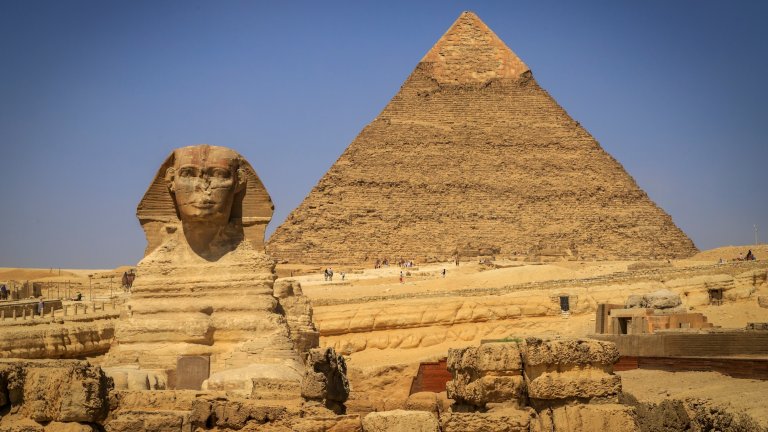 Photo of the Sphinx in front of the Great Pyramid of Giza on a sunny day
