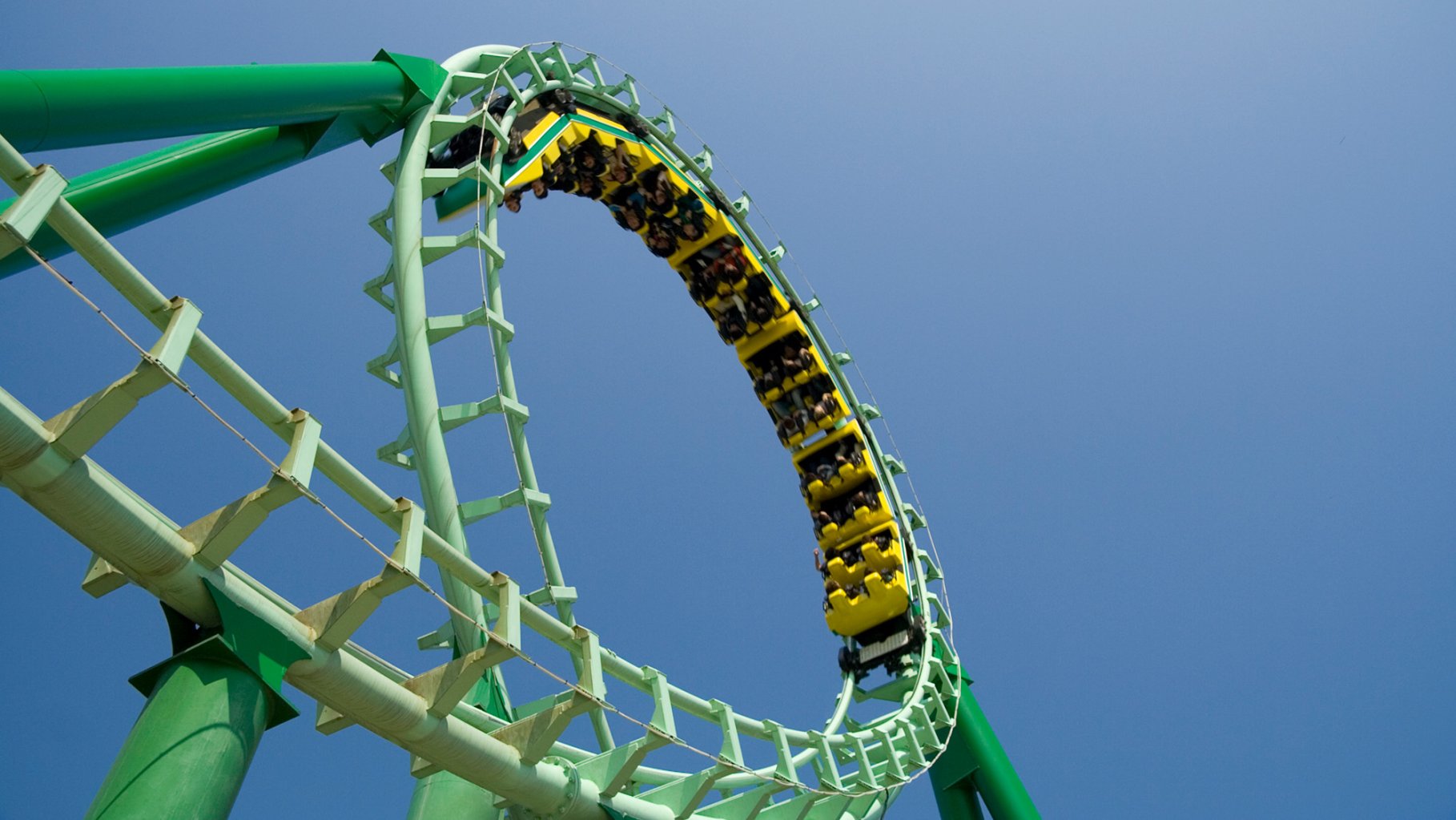 Spiral loop of a green steel roller coaster with a coaster on the track.