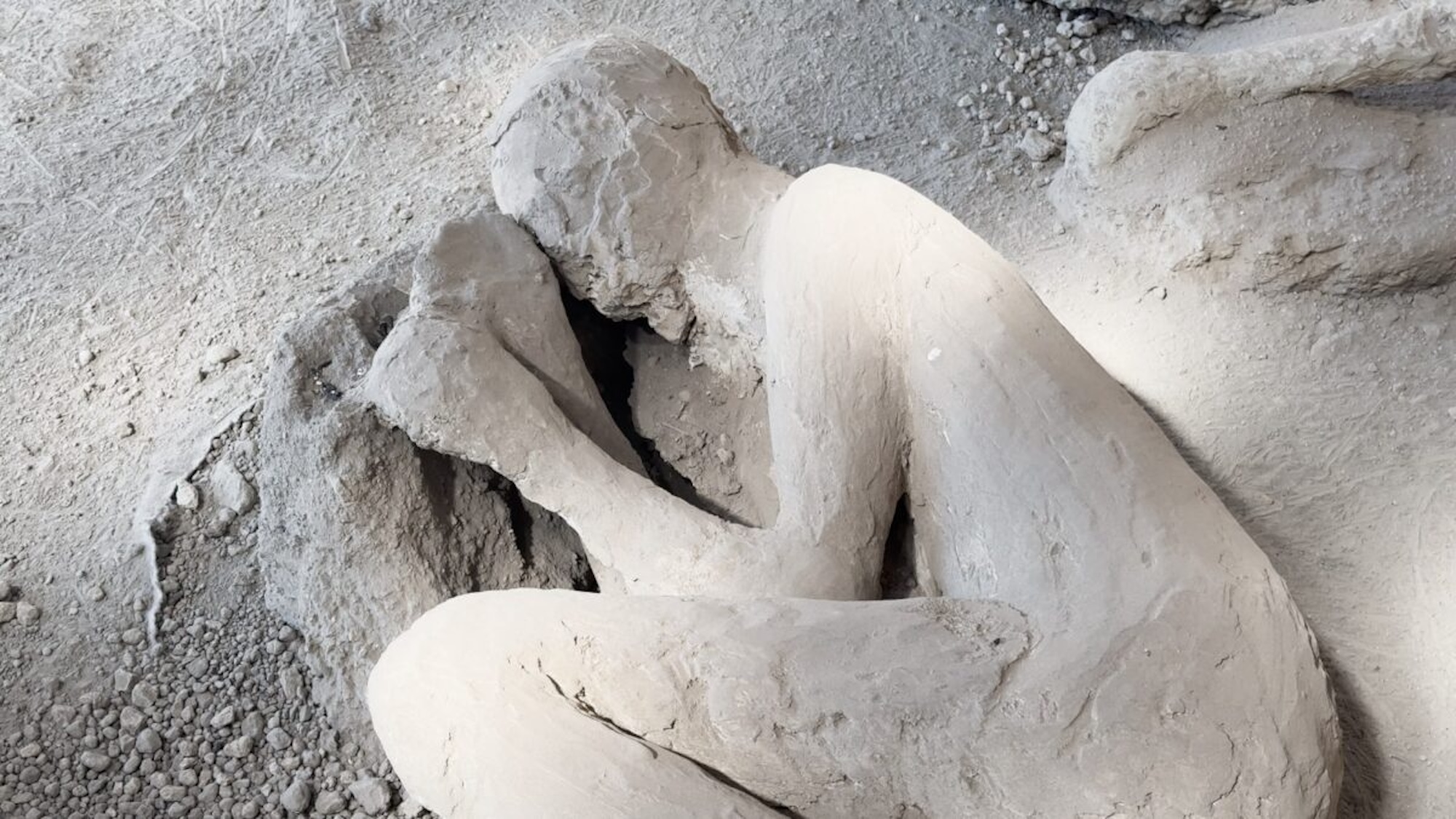 Plaster cast of Pompeii victim curled up on the ground