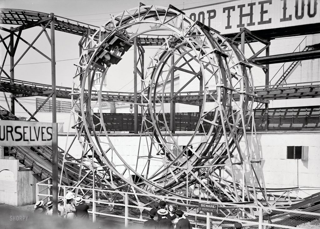 Black and white photograph of an upside steel rollercoaster with a double loop.