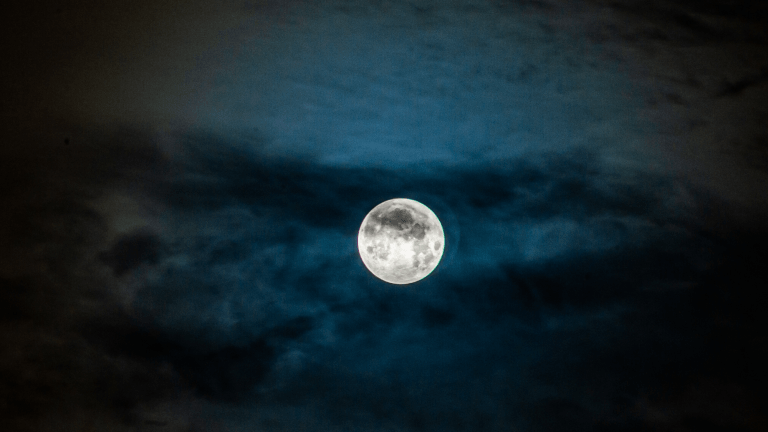 a full moon against a black and slightly blue sky