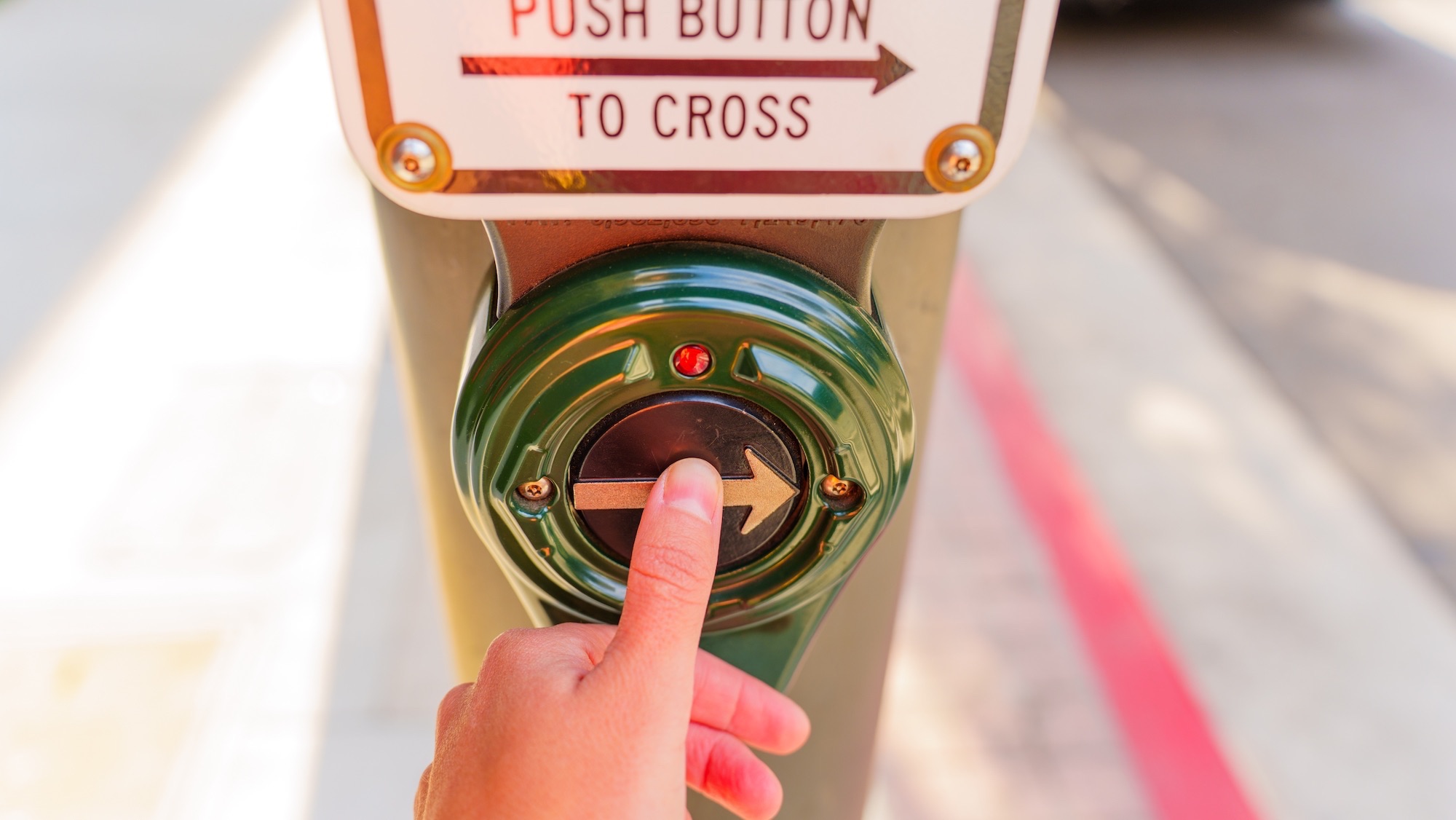 Los Angeles, California - Close-up of a hand pressing a pedestrian push button at a crosswalk in Los Angeles,