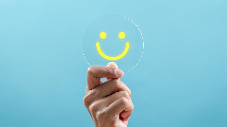 Hand holding Happy smile face on a blue background.