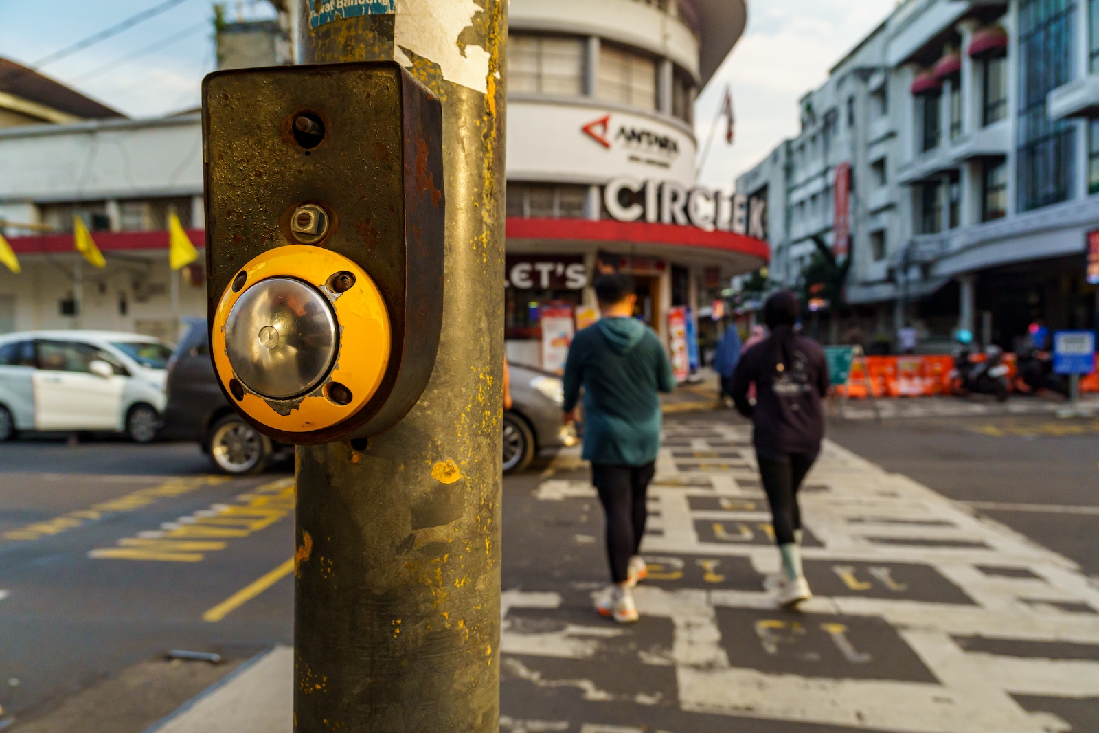 crosswalk button to turn on the green light with a background of people crossing the street;