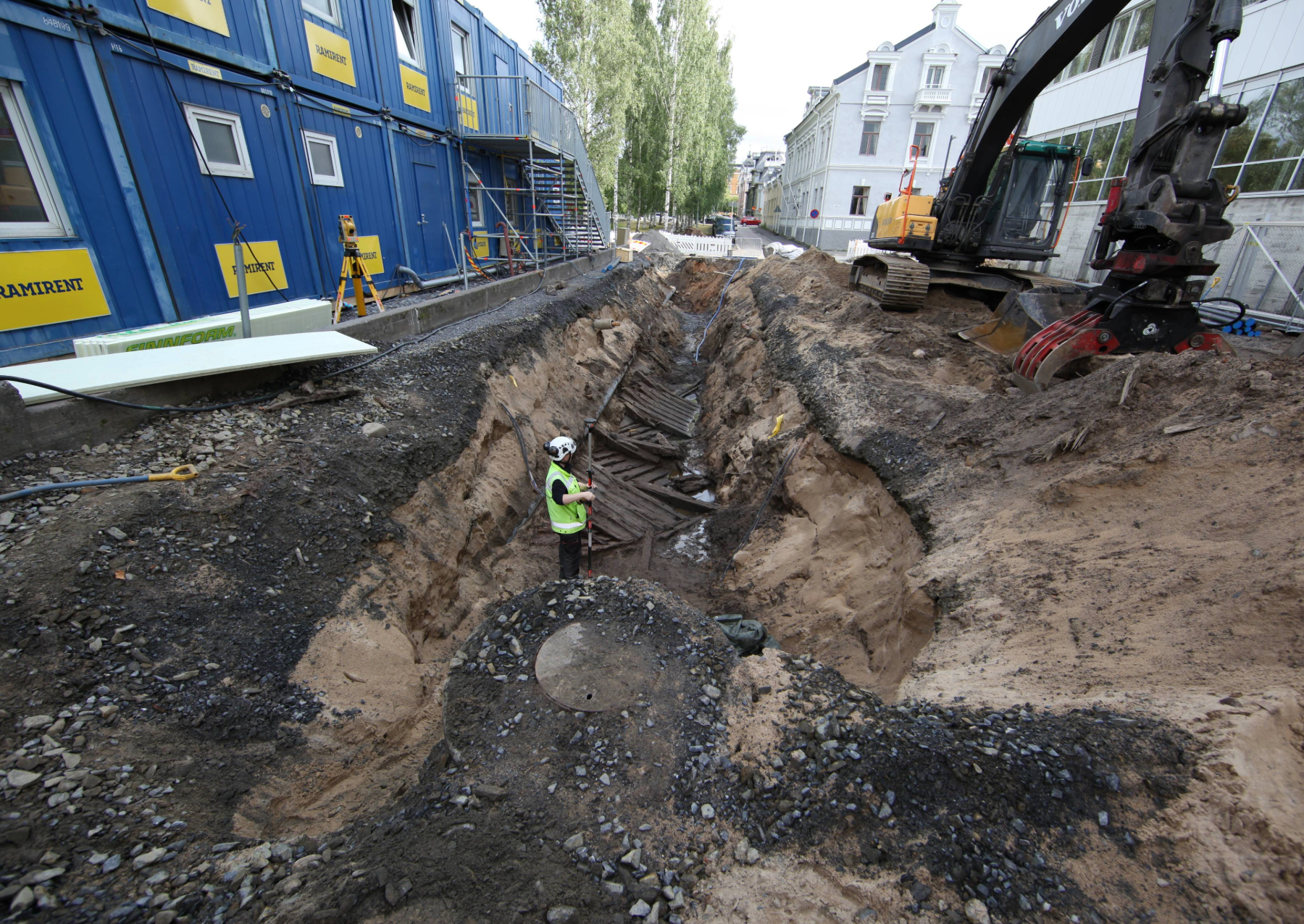 a shipwreck being excavated between two modern buildings