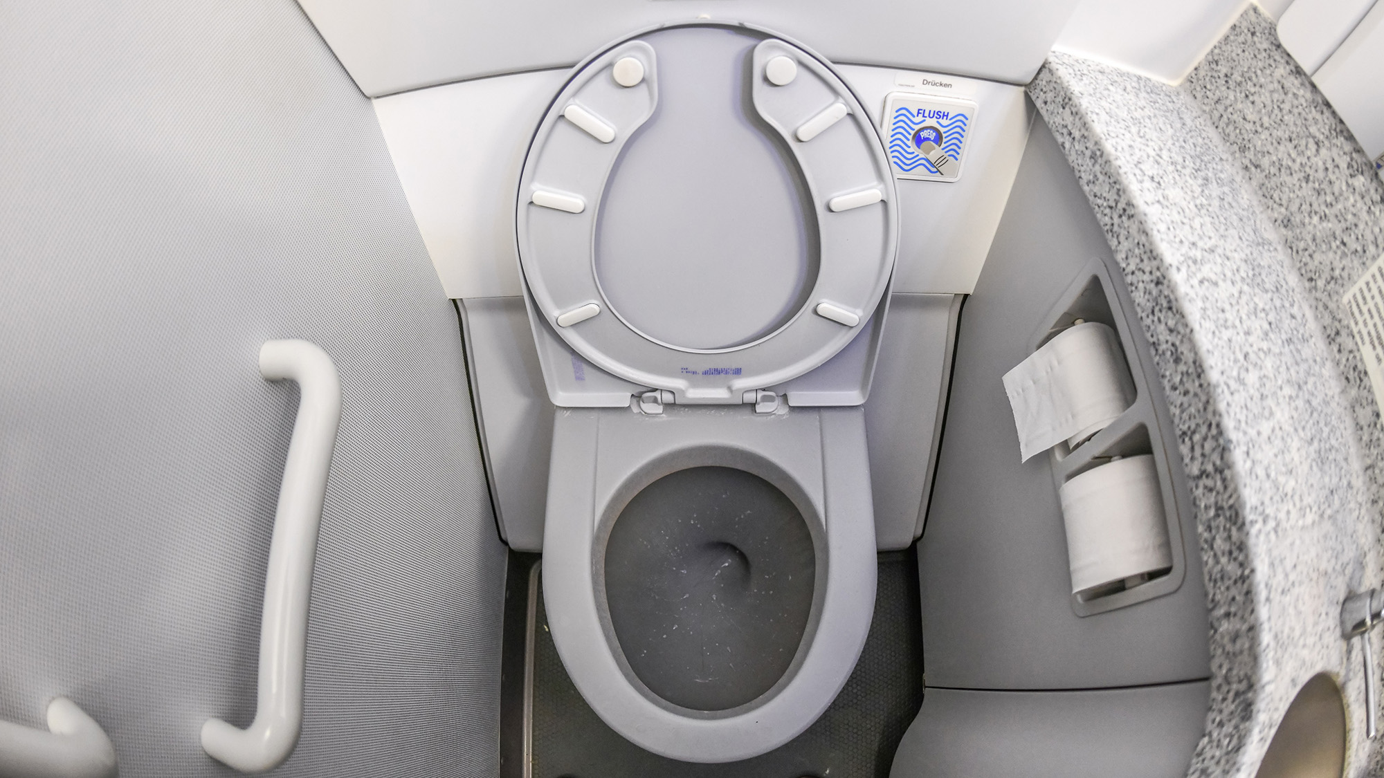 Close up of an airplane toilet with the lid open.