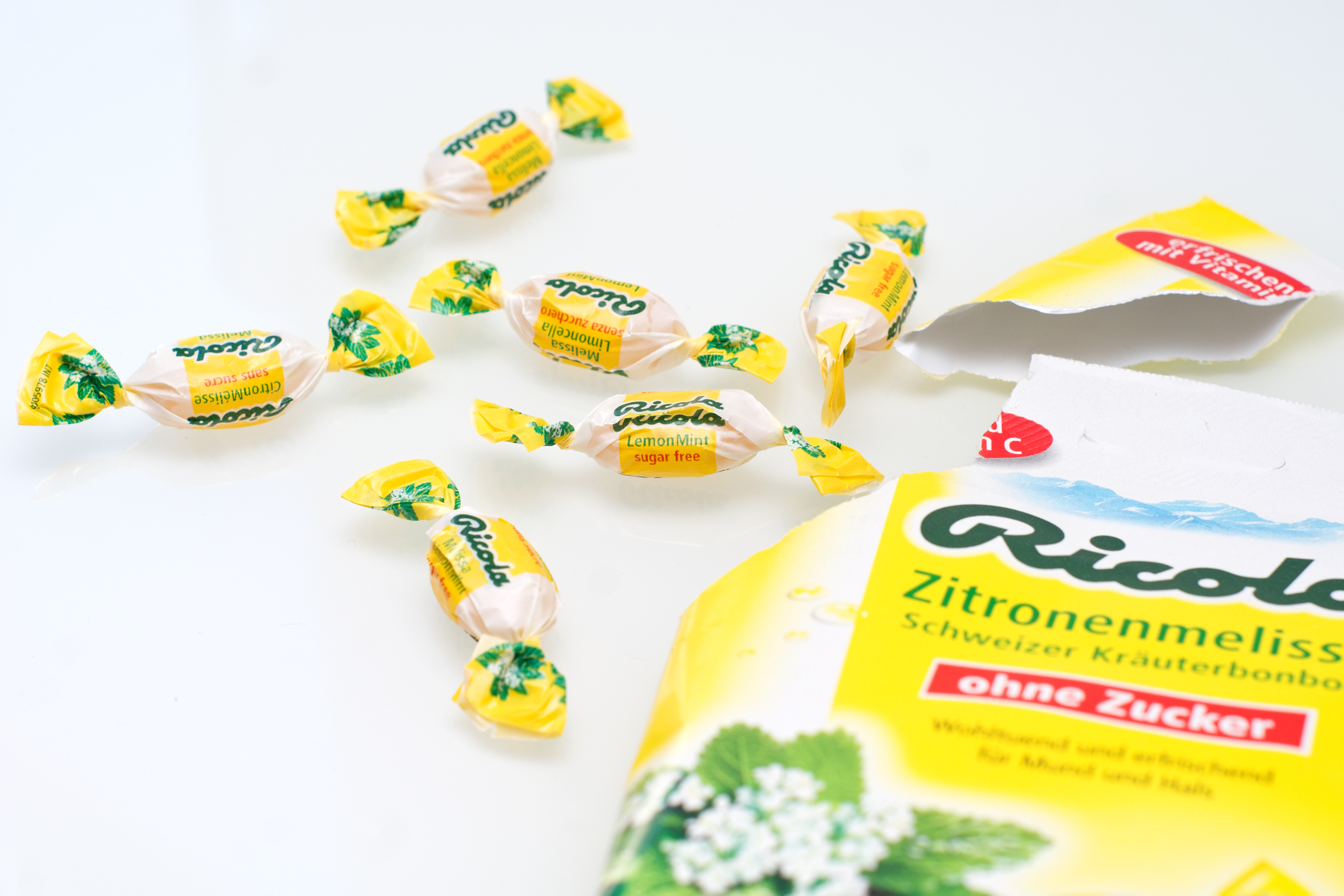 An opened package of Ricola Zitronenmelisse hard candy and some single bonbons.