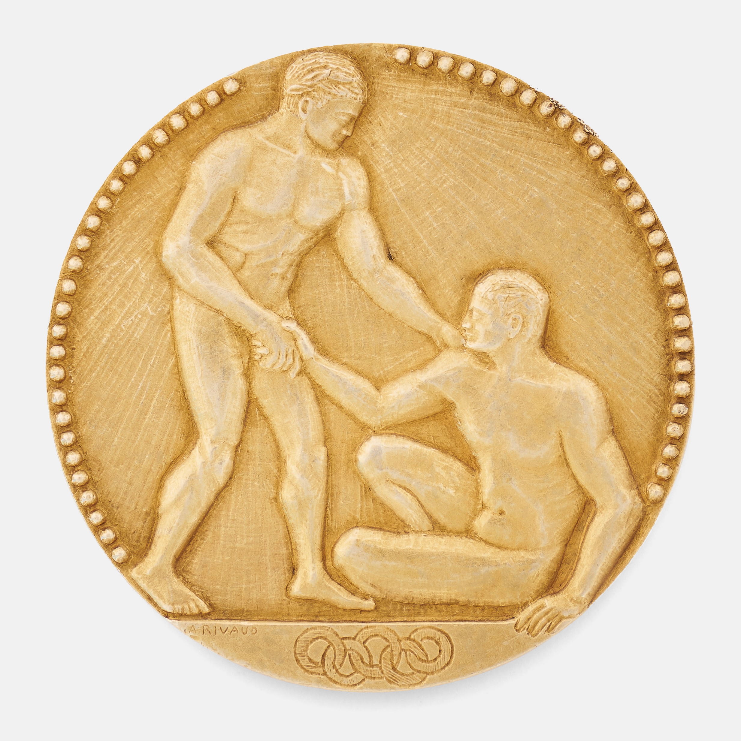 a gold medal from 1924. a winner is seen reaching out to lift up a fallen competitor. the five interlocking Olympic rings are below