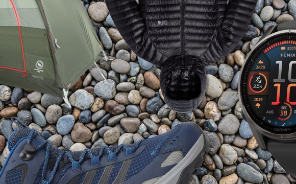 REI anniversary sale products including a watch, tent, jacket, and boot on a background of stones.