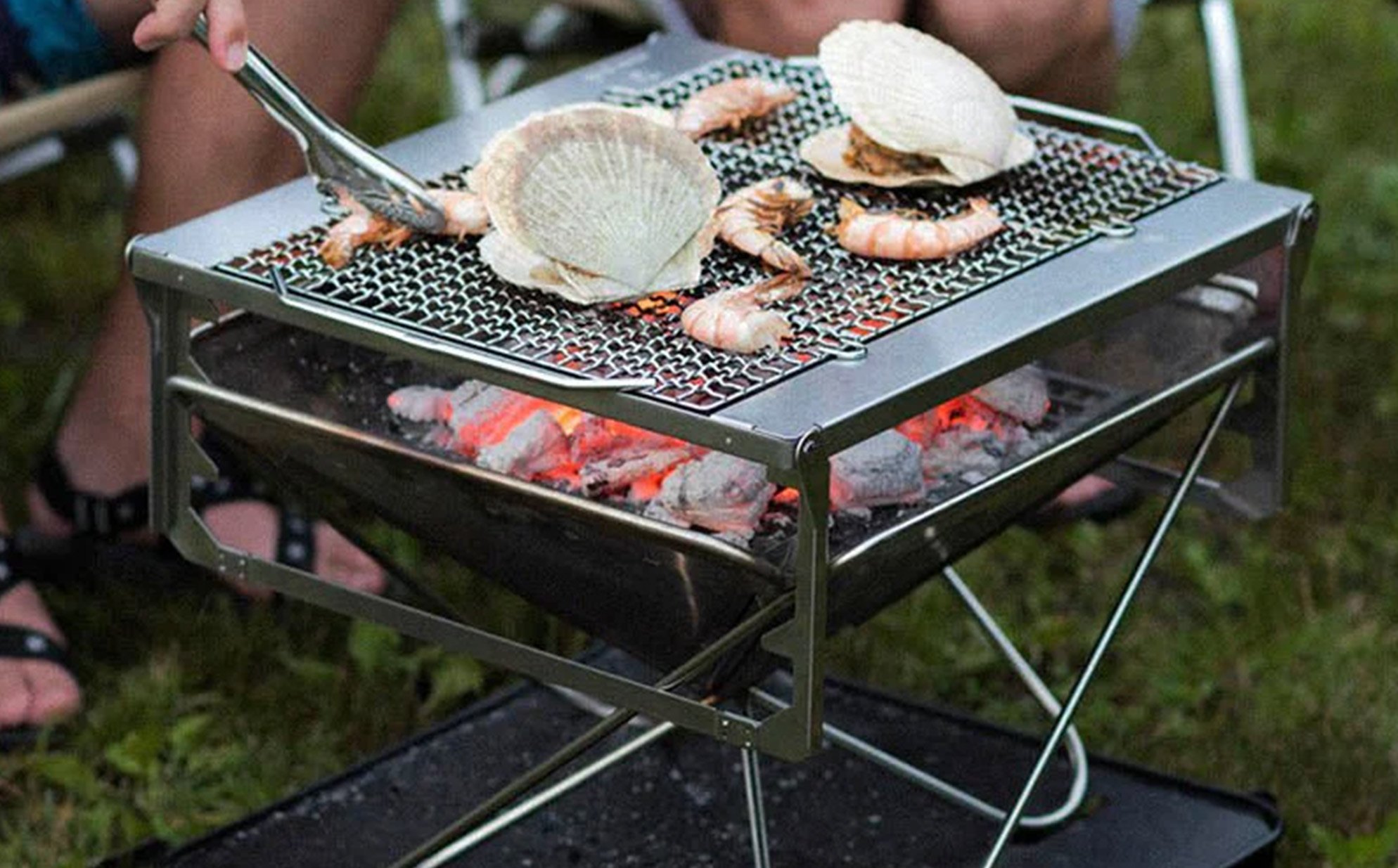 Snow Peak grill at a campsite with seafood cooking.
