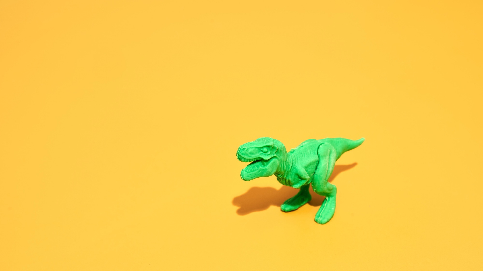 Green Plastic Tyrannosaurus Rex On Yellow Background