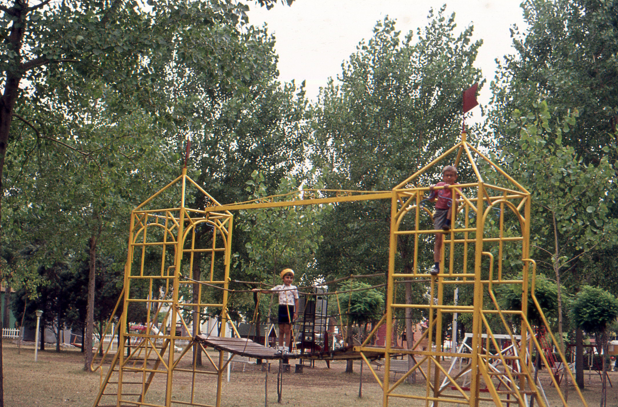 Vintage color photograph of two boys playing in public park featuring a playground.
