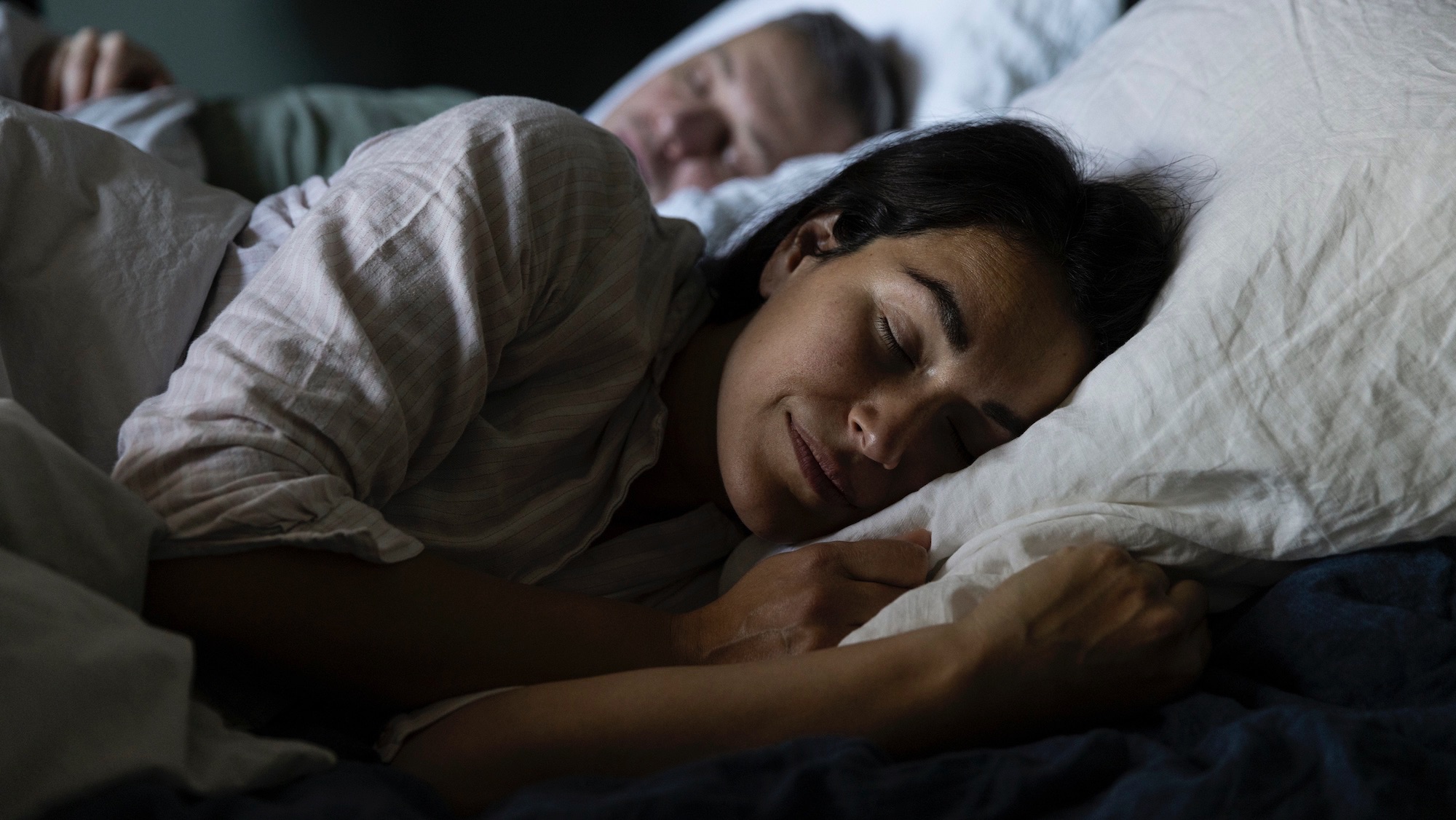 Woman sleeping on bed beside man in bedroom at home