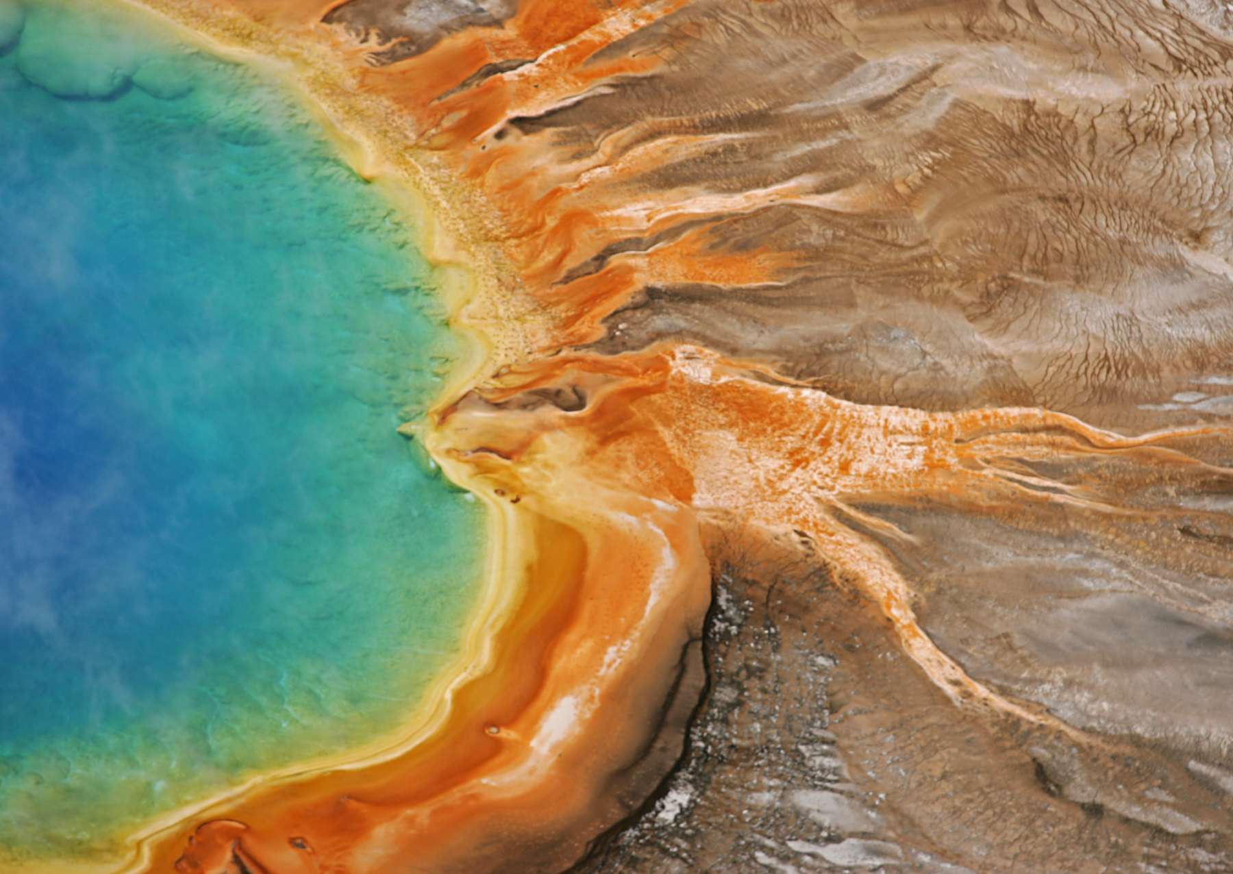 a hot spring with blue, green, yellow, and orange water