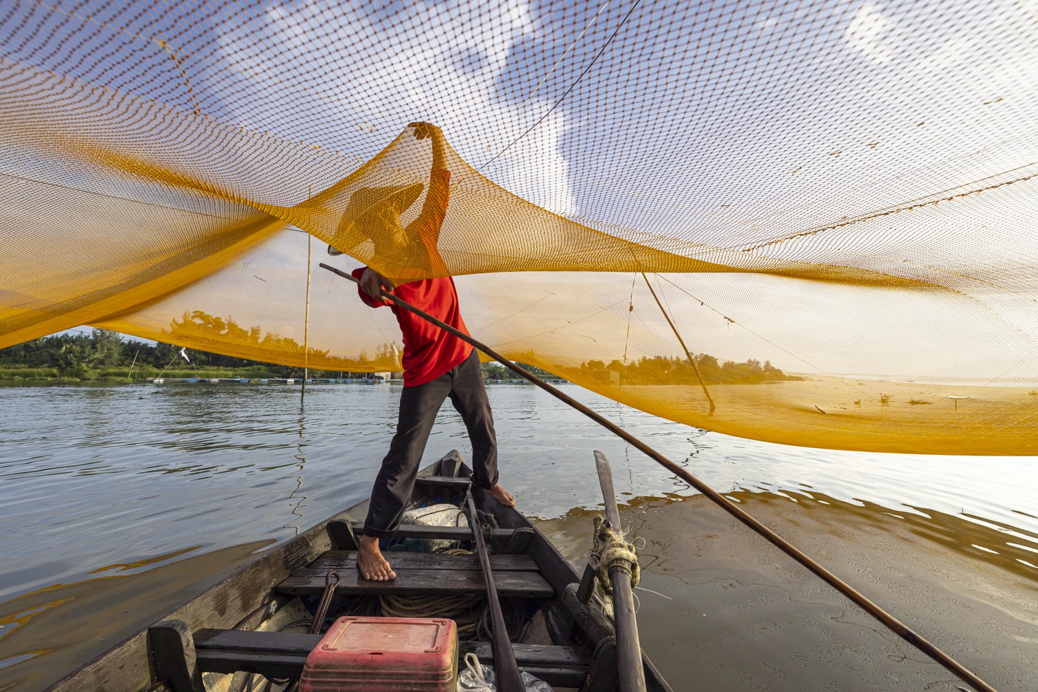 a fisherman holds up a net