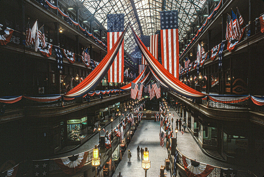 View, from a balcony, along the interior of the Cleveland Arcade decorated with bunting and American flags for the US Bicentennial, Cleveland, Ohio, October 1976. Built in 1890 and modelled after Milan's Galleria Vittorio Emanuele II (completed in 1877), the Arcade was one of the first covered shopping center in the United States and was afforded National Historic Landmark status in 1975. (Photo by Howard Ruffner/Getty Images)