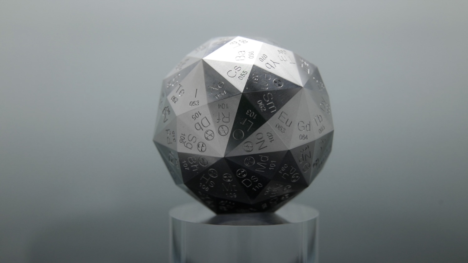 Aluminum 120-sided die displaying elements on a pedestal