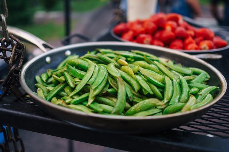 Beans cooking over a fire in a Hexclad pan