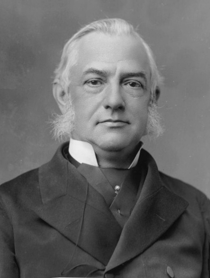 Black and white photograph of white middle aged man with large sideburns
