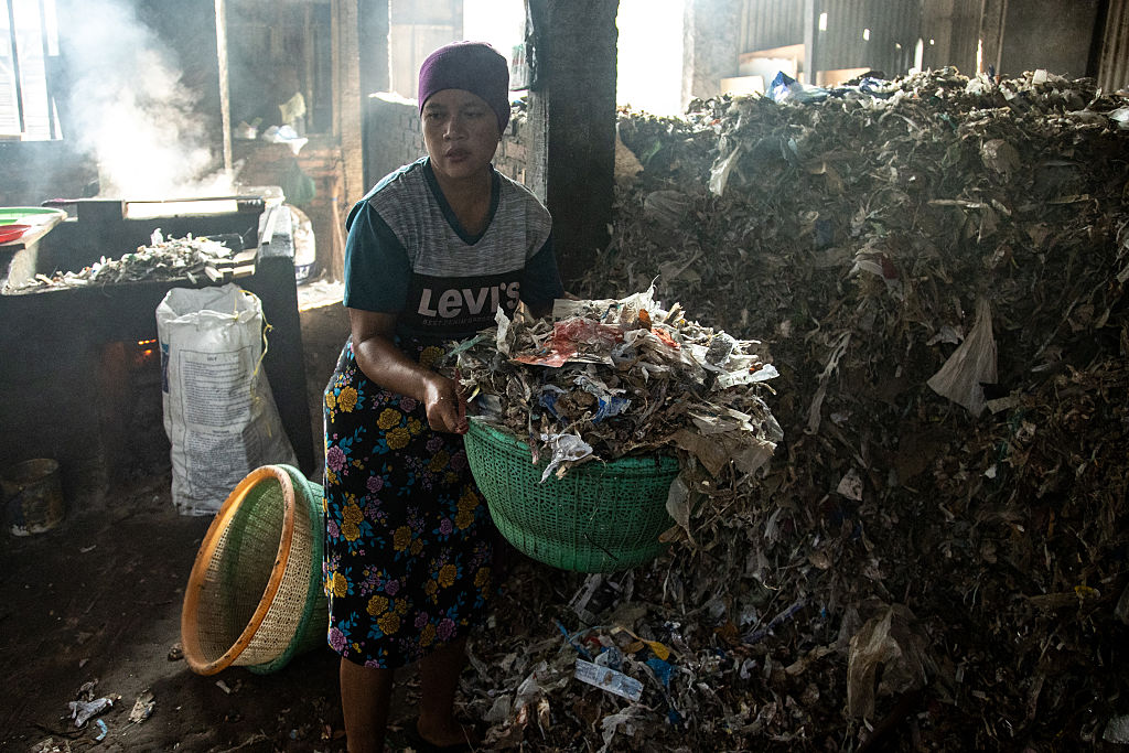 SIDOARJO, INDONESIA - MAY 22: A worker carries a basket of a combination of plastic waste, wood, and coconut husks to be used as fuel to fry tofu at a traditional tofu factory on May 22, 2025 in Sidoarjo, Indonesia. Approximately 60 traditional tofu factories in Klagen, Tropodo village, Krian district, use a combination of plastic waste, wood, and coconut husks to fuel furnaces, boilers, and fryers in an effort to cut fuel costs, despite national bans on open waste burning. According to World Bank data, the largest exporters of plastic waste to Indonesia are the EU, US, UK, Australia, and Japan. Medical experts warn that burning plastic—especially in food production—raises serious health concerns, including increased risks of respiratory illnesses, immune dysfunction, and chronic diseases. In February 2025, environmental group Ecoton tested tofu purchased from a Tropodo market and found high concentrations of microplastics, in the form of fibers ranging from 0.15mm to 1.76mm. Environmental groups have also reported hazardous pollution from toxic ash accumulating around tofu factories and entering the food chain through free-range chickens. When burned, plastic releases a toxic mix of pollutants—including dioxins and microplastics—that contaminate air, soil, food, and water. (Photo by Robertus Pudyanto/Getty Images)