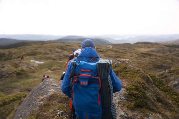 A blue and red Odin AT40 Ski Touring Backpack sporting a red RECCO badge shown on a hike in the fjords above Bruvik, Norway