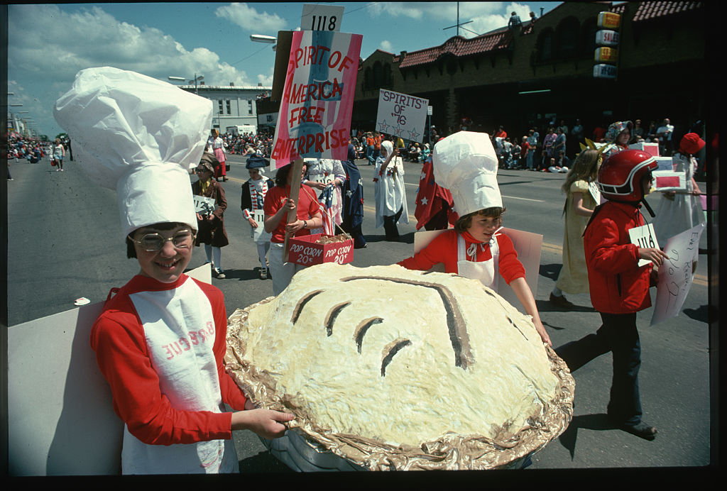 Children in a Bicentennial parade push a large paper-mache apple pie in celebration of American independence. Behind them other children are dressed in Colonial fashion. (Photo by © Wally McNamee/CORBIS/Corbis via Getty Images)