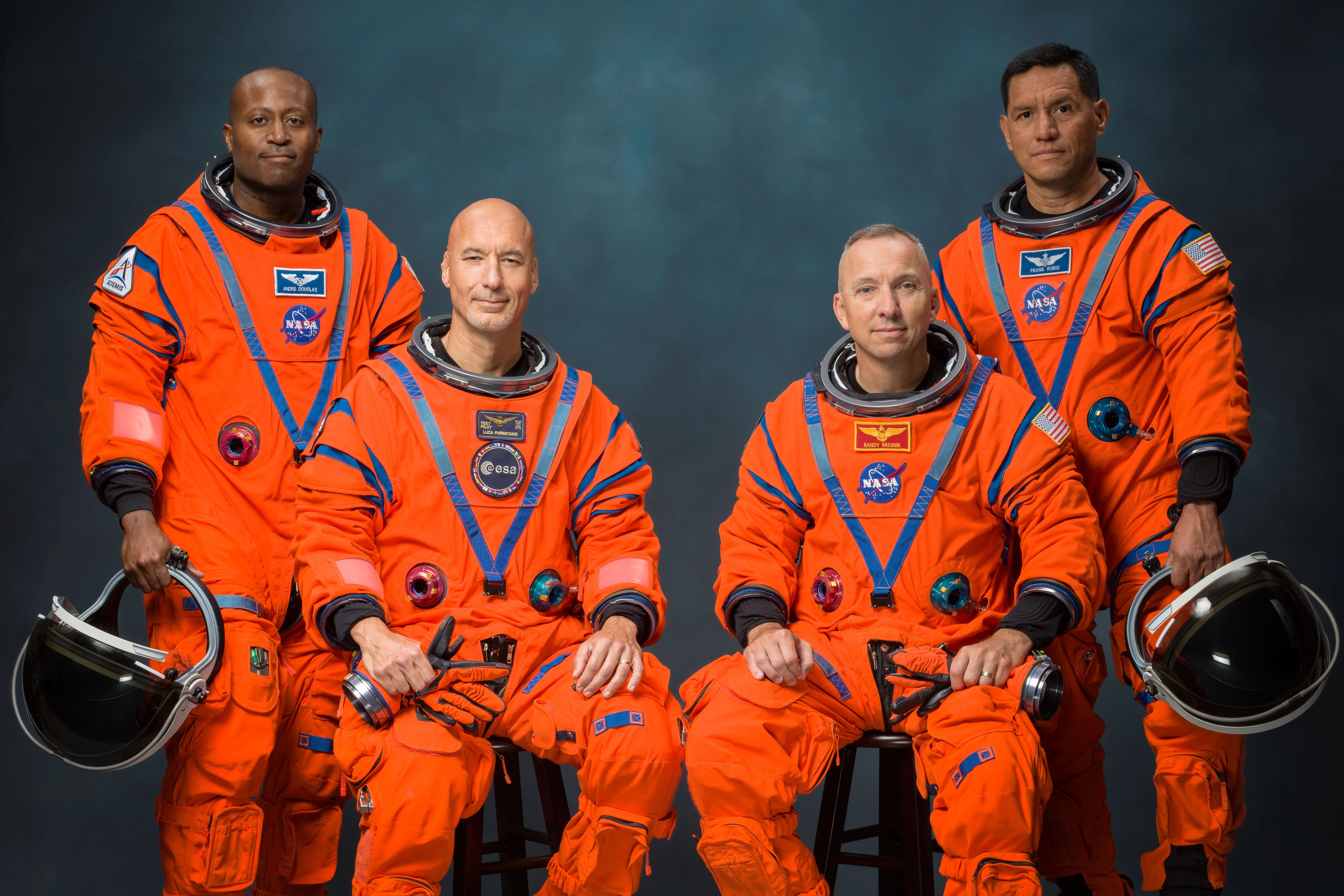 The Artemis III crew poses for an official portrait (from left: Andre Douglas, Luca Parmitano, Randy Bresnik, Frank Rubio). They are wearing orange astronaut suits