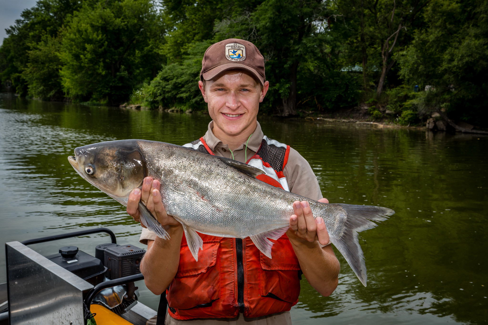 a man on a boat holds a large silver fish