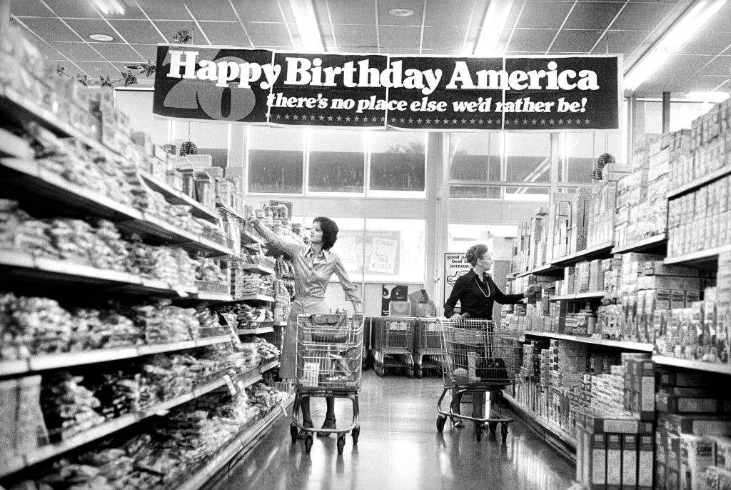Two women shopping in grocery store under banner reading: "Happy birthday America, there's no place else we'd rather be!" commemorating the United States Bicentennial, Marion S. Trikosko, U.S. News & World Report Magazine Photograph Collection, May 1976. (Photo by: Circa Images/GHI/Universal History Archive/Universal Images Group via Getty Images)