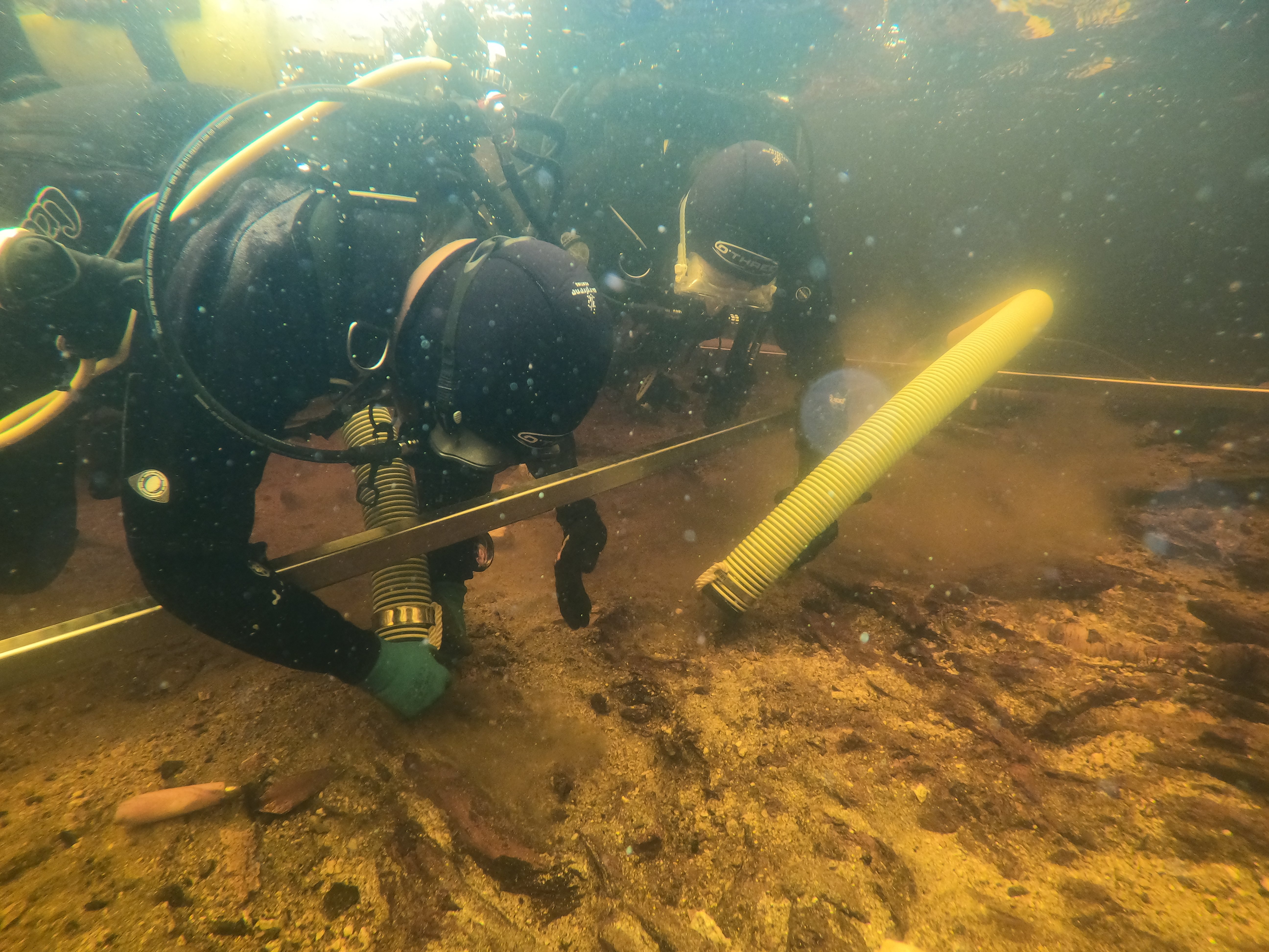 two divers in full gear examining and under water dig site in a scottish lake