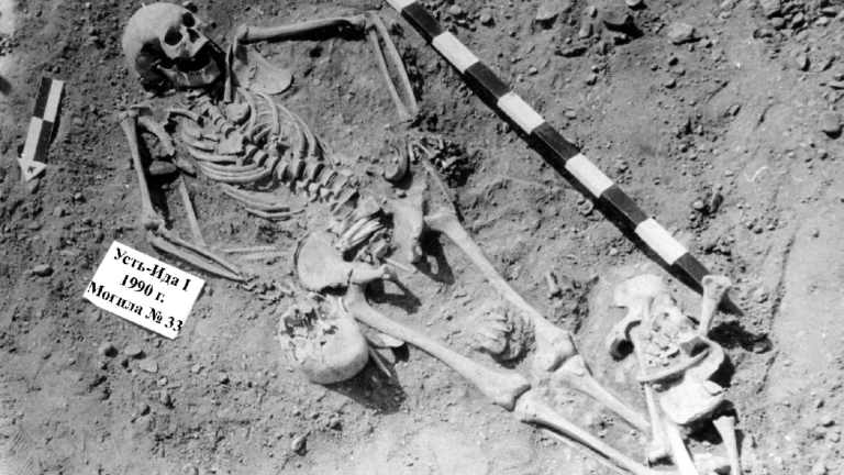 a black and white photograph of two skeletons in a grave