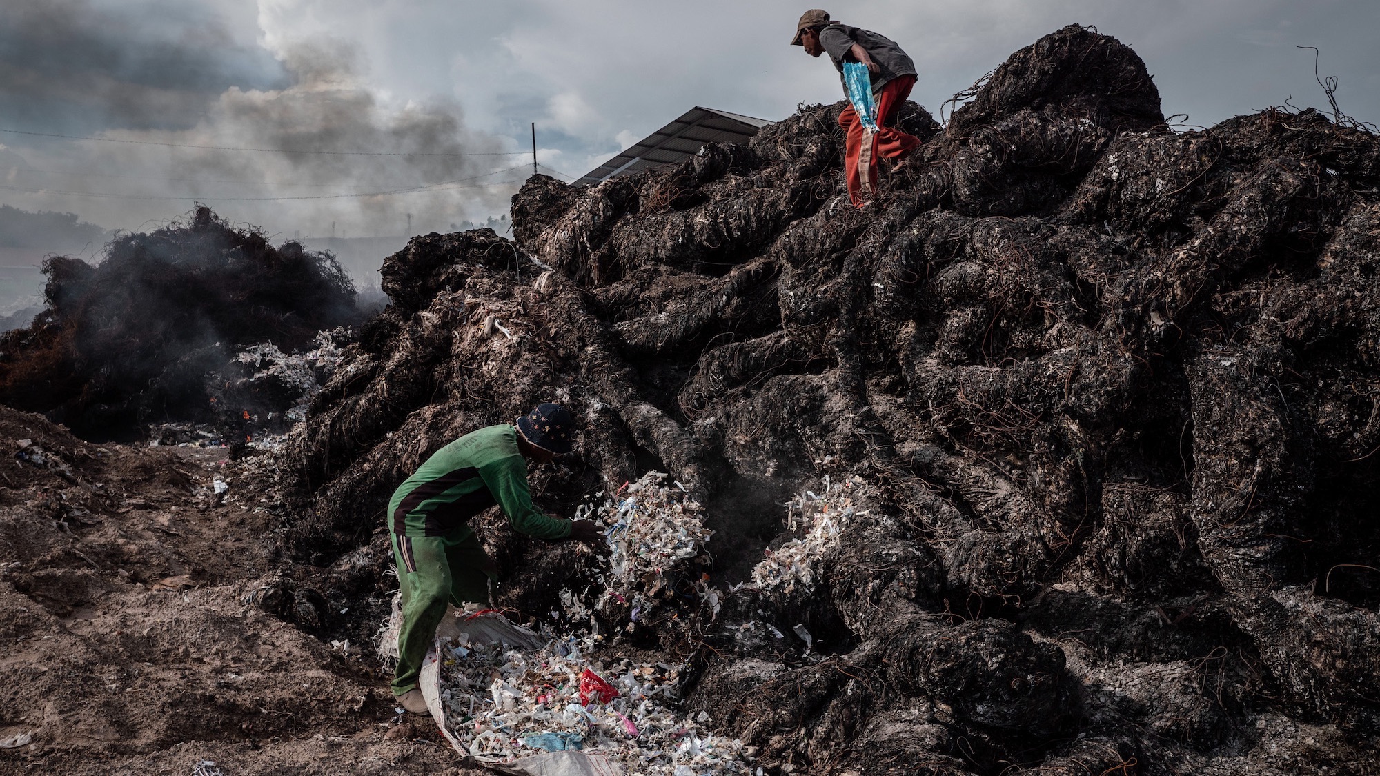Workers prepare to burn plastic waste at a import plastic waste dump in