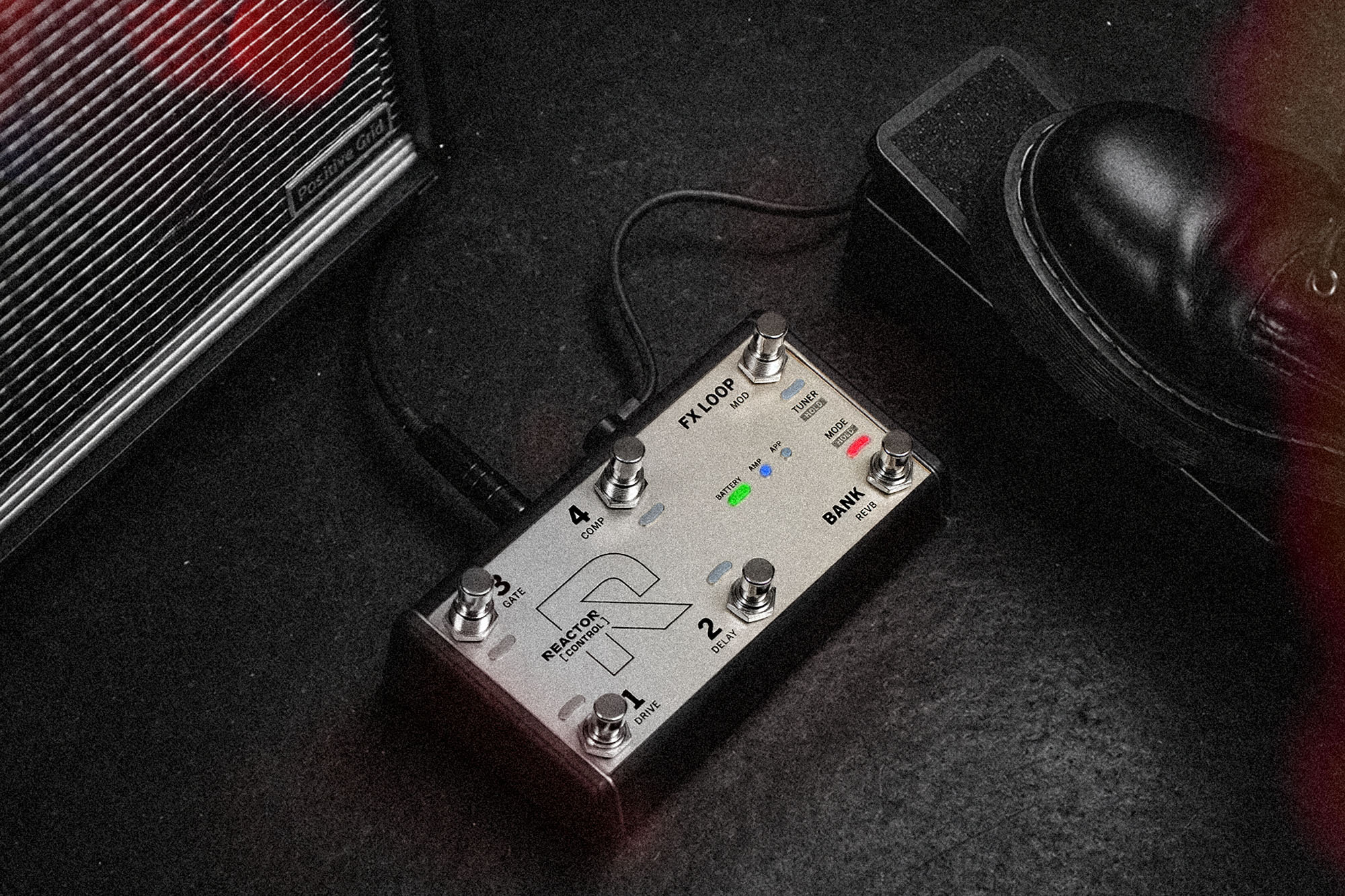 A Positive Grid REACTOR Control foot pedal shown on a stage in front of an amp