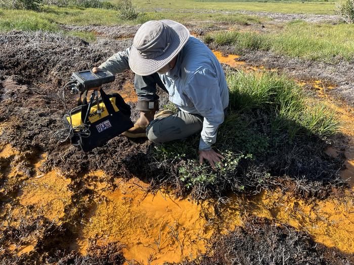a scientist samples river water that has turned orange