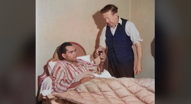 man in bed take a cup of liquid from another man