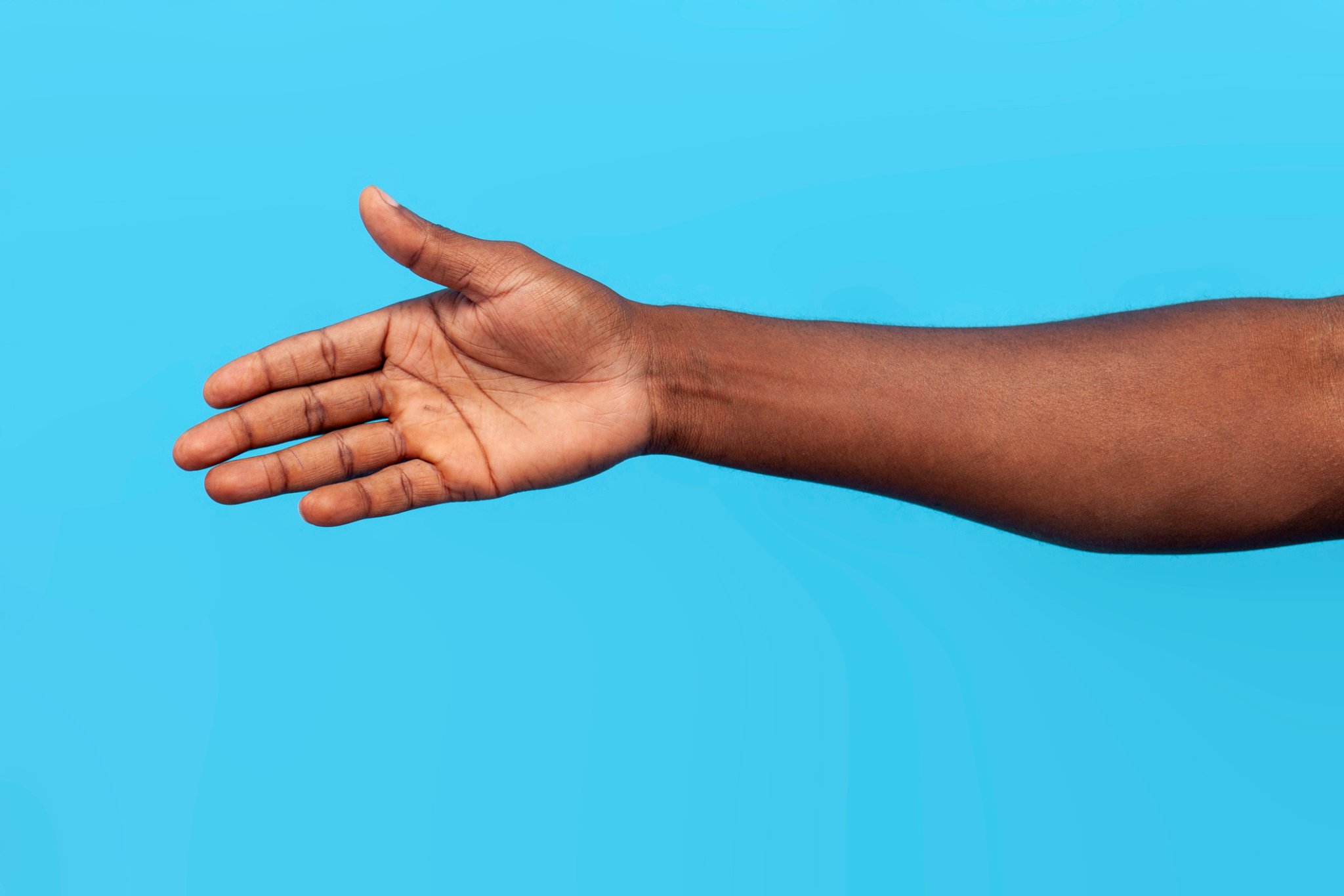african american male hand showing empty palm and handshake gesture on blue isolated background, closeup