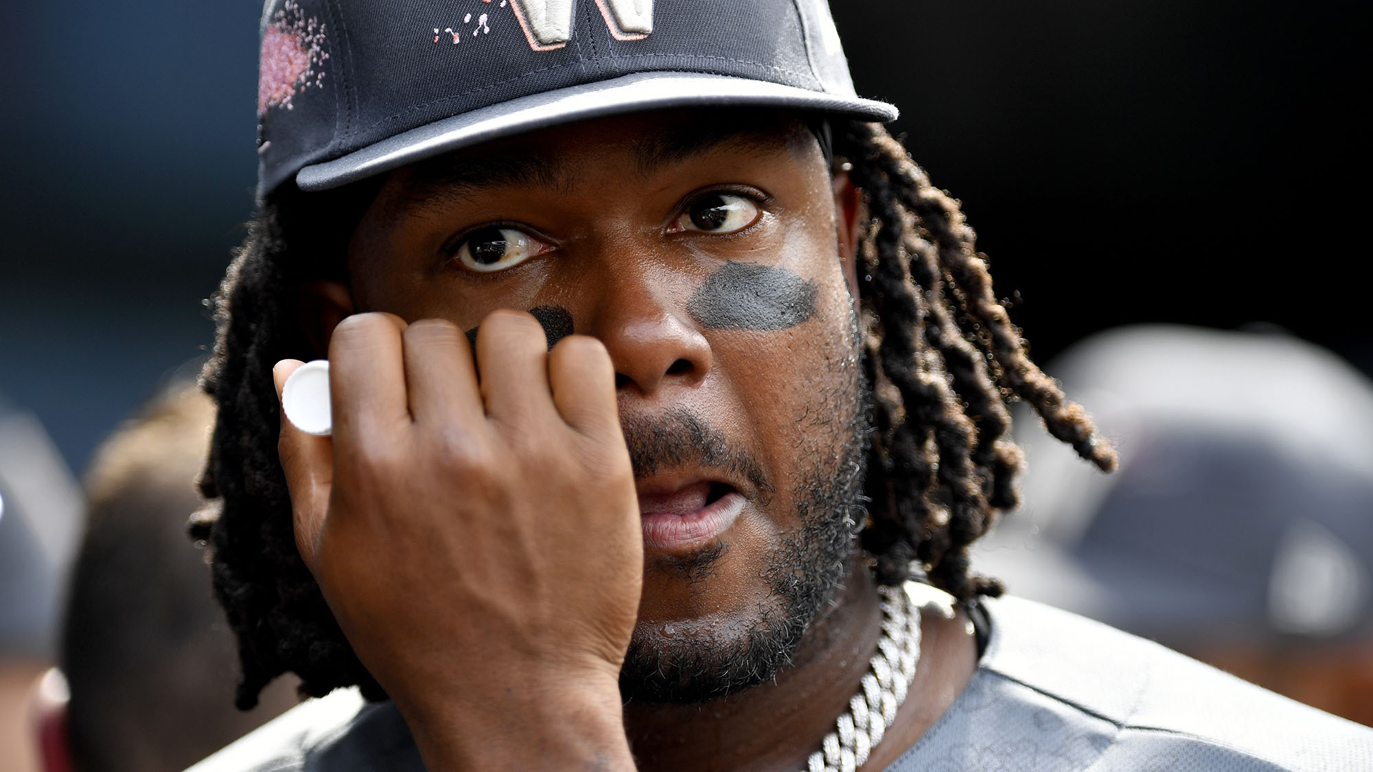 Black man with dreads and a hat gets black put under his eyes.