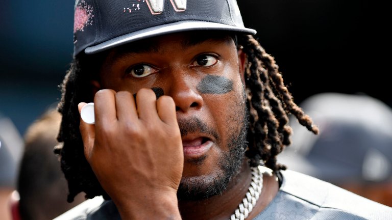 Black man with dreads and a hat gets black put under his eyes.
