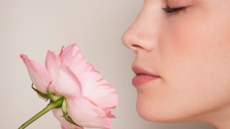 Beautiful white young woman smelling a pink flower