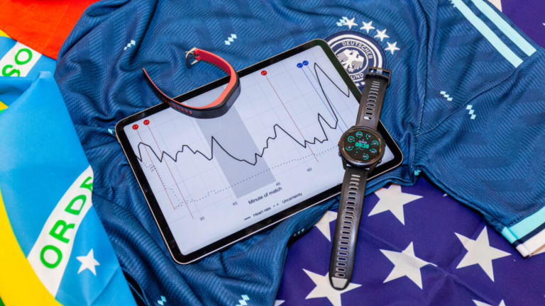 two smart watches and a tablet laying on various flags and soccer jerseys