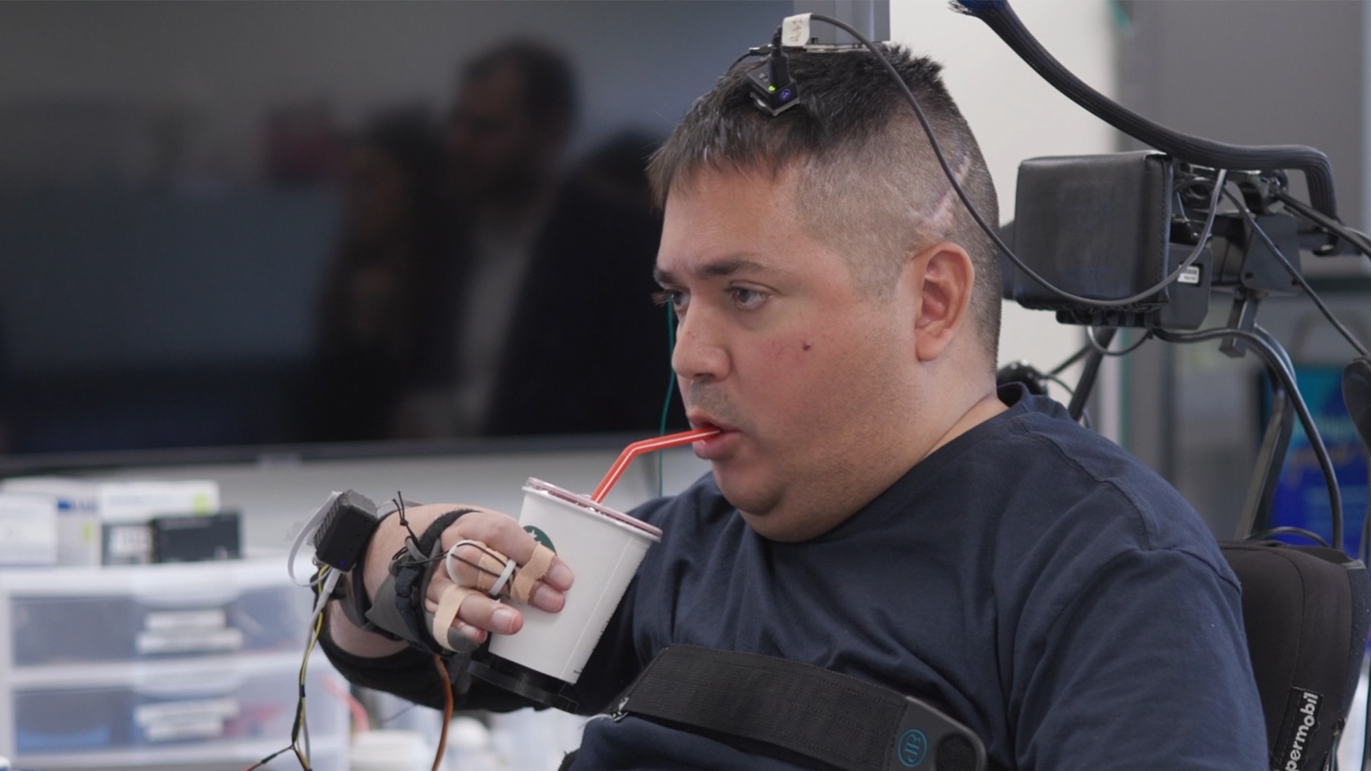 Keith Thomas, who has lived with paralysis since a diving accident in 2020, is now able to grasp, lift and drink from a cup on his own. After joining a clinical trial at Northwell Health’s Feinstein Institutes for Medical Research that uses brain implants and artificial intelligence to bypass his injury and reconnect his brain with healthy parts of his spinal cord, Thomas has continuously improved, restoring lasting movement and feeling in his arm and hand.