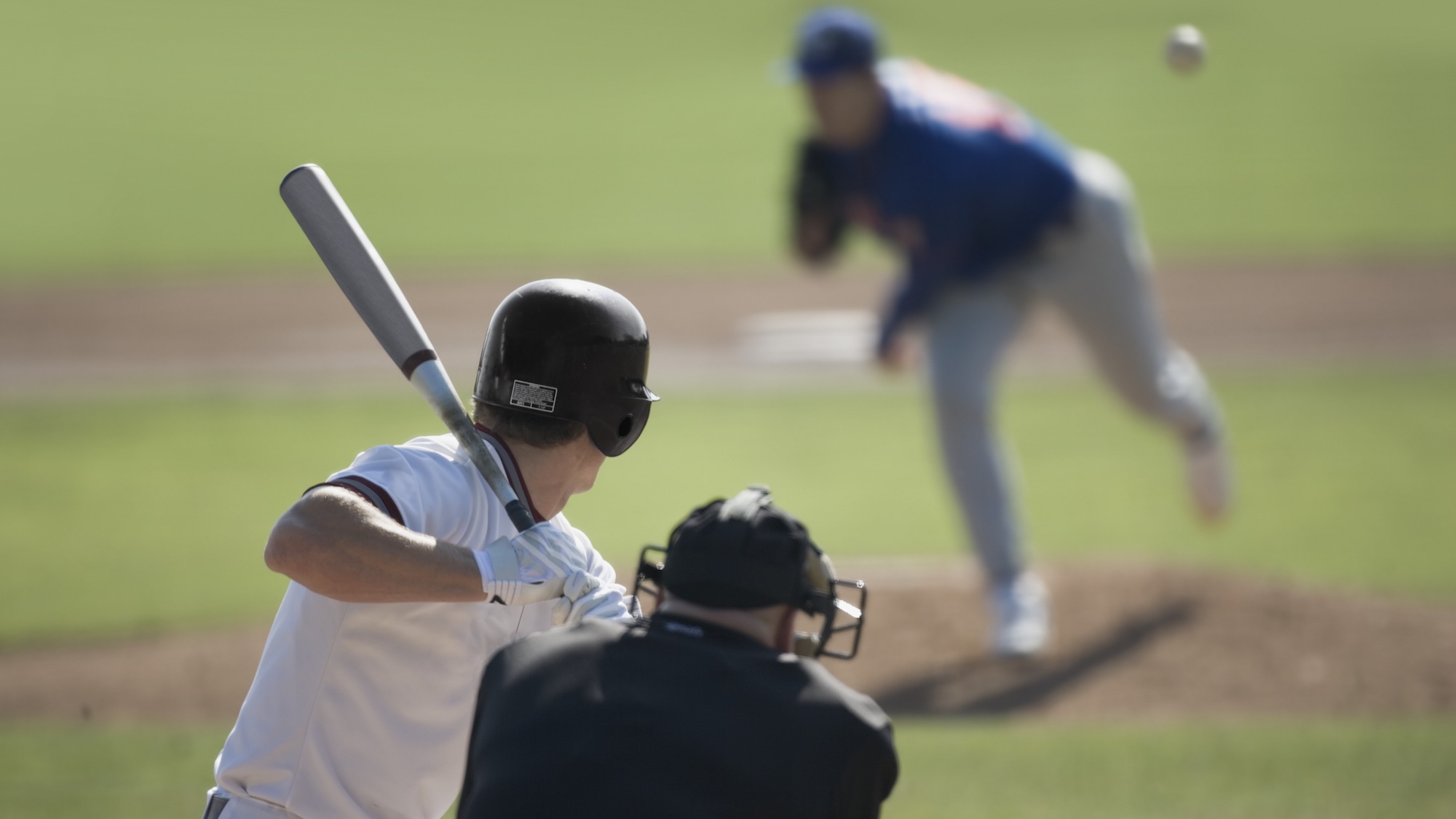 Baseball batter readying as pitcher throws ball at him