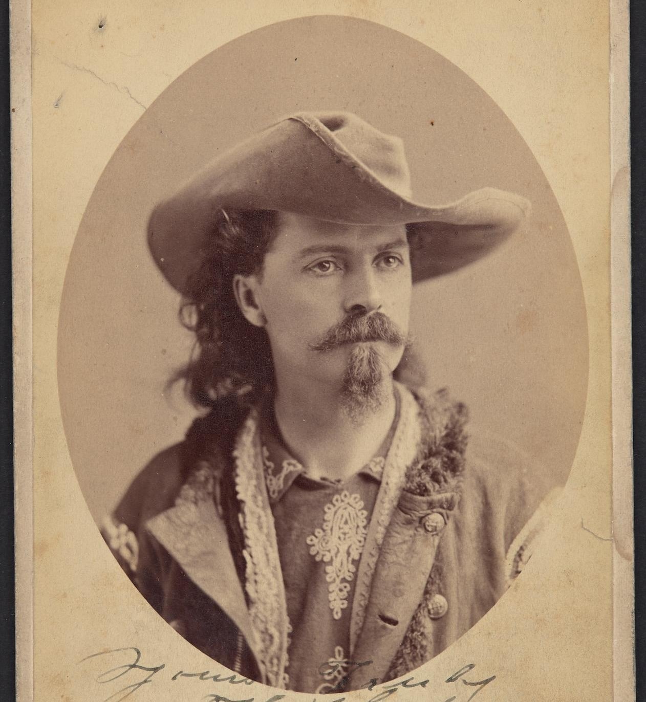 Vintage photograph of a young man in a cowboy hat with a mustache and goatee.