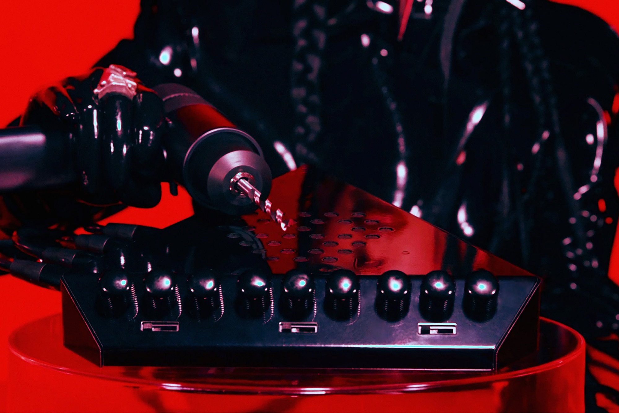 A close-up of the Eternal Research Demon Box knobs and sliders with a devilish drill poised above it on a red background