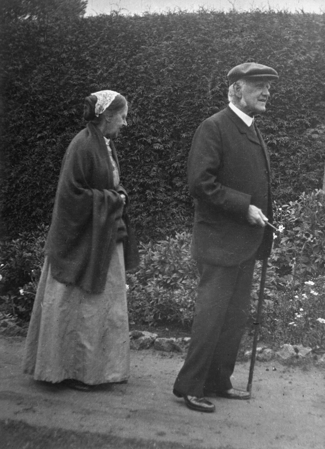 Vintage black and white photograph showing twto old people walking in the garden.