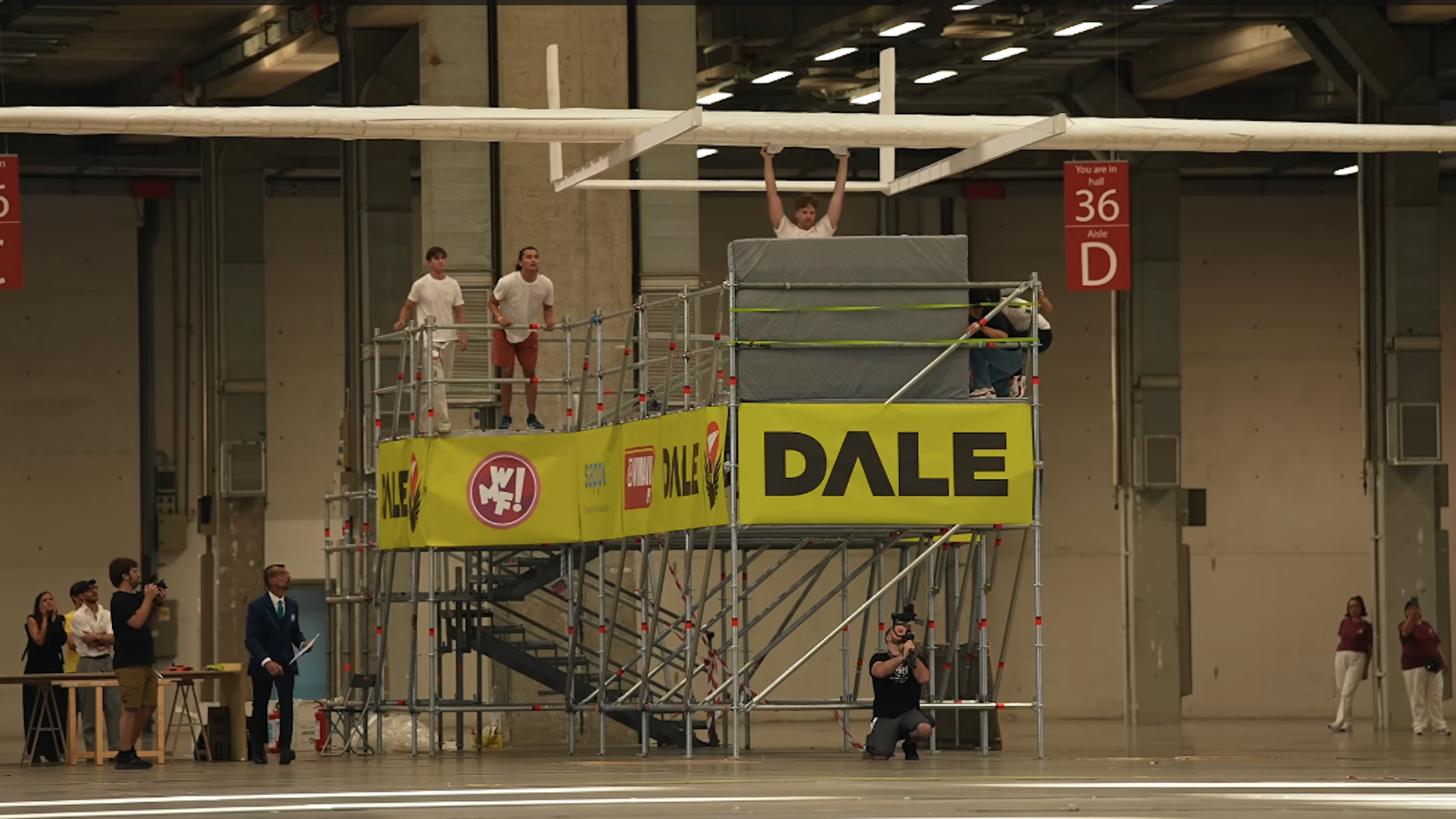 Students preparing to launch world's largest paper airplane from platform inside warehouse