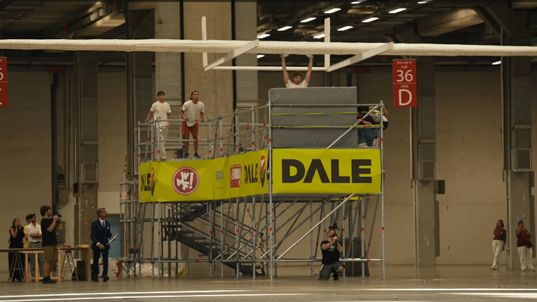 Students preparing to launch world's largest paper airplane from platform inside warehouse